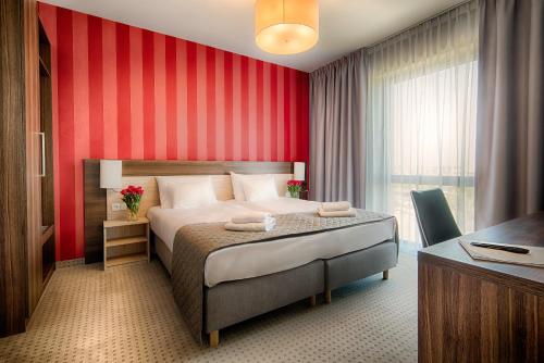 a bedroom with a bed with a red wall at Focus Hotel Premium Gdańsk in Gdańsk