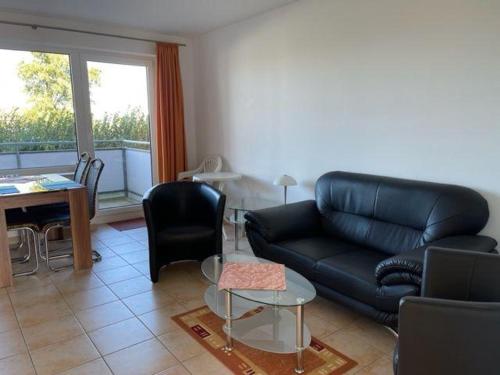 uma sala de estar com um sofá de couro preto e uma mesa em Haus-am-Waldbad-Whg-12-7 em Cuxhaven