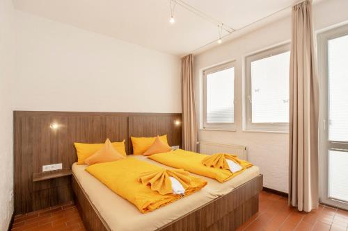 sypialnia z dużym łóżkiem z żółtą pościelą w obiekcie Lütje Hus w mieście Langeoog