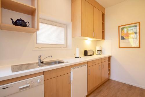 cocina con armarios de madera, fregadero y ventana en Lütje Hus, en Langeoog