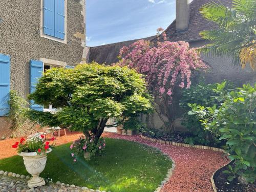 a garden with a tree and flowers in front of a building at Domaine de la Carrère in Arthez-de-Béarn