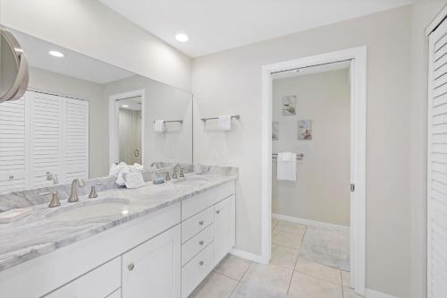 a white bathroom with two sinks and a large mirror at 152 Leeward Court in Marco Island