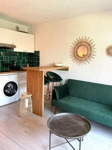 un salon avec un canapé vert et une cuisine dans l'établissement Appartement calme et chaleureux, à Six-Fours-les-Plages