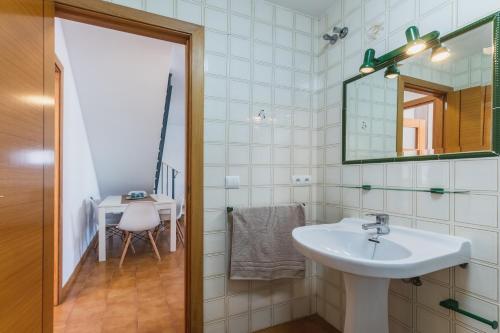 een badkamer met een wastafel, een spiegel en een tafel bij Dúplex junto a la playa in Sanlúcar de Barrameda