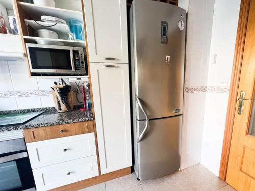 a kitchen with a stainless steel refrigerator and a microwave at Private garden 100 m from the sea in Benicàssim