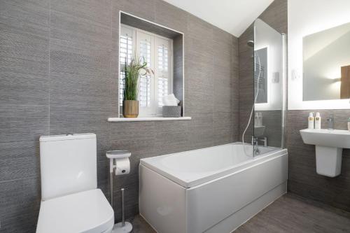 a bathroom with a tub and a toilet and a sink at Contemporary Home by LetMeStay in Carnforth