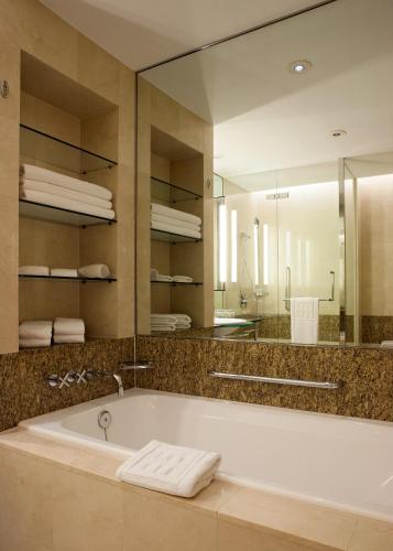 a bathroom with a tub and a large mirror at Ambassador Hotel Hsinchu in Hsinchu City
