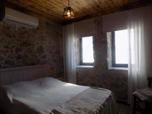 a bedroom with a bed and two windows at Denize sıfır restore edilmiş ahşap tavan taş villa in Bodrum City