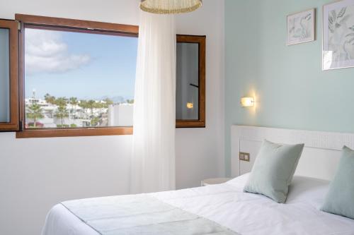 una camera da letto con un letto bianco e una finestra di Apartamentos Isla de Lobos - Adults Only a Puerto del Carmen