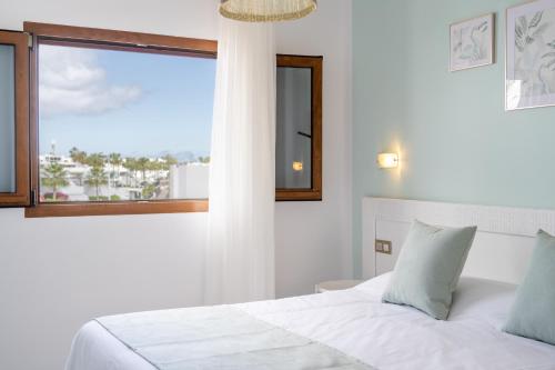 a bedroom with a white bed and a window at Apartamentos Isla de Lobos - Adults Only in Puerto del Carmen
