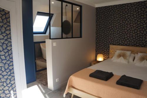 een slaapkamer met een bed met twee zwarte handdoeken erop bij Maison : L'Ecrin de l'Océan, 80 mètres de la Plage. in Le Pouliguen