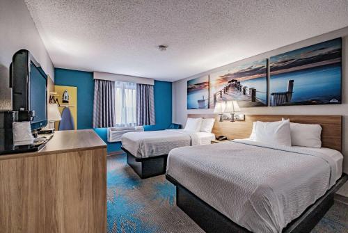 a hotel room with two beds and a flat screen tv at Days Inn by Wyndham Brunswick Bath Area in Brunswick