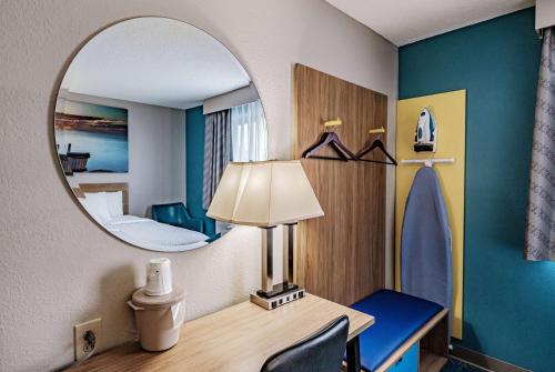 a room with a mirror and a desk with a lamp at Days Inn by Wyndham Brunswick Bath Area in Brunswick