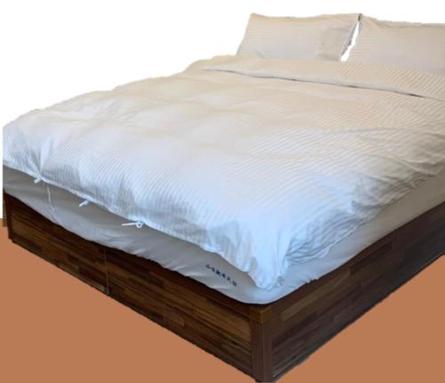 un letto con lenzuola bianche su una piattaforma di legno di 品味觀峰民宿 a Kung-t'ien-ts'un