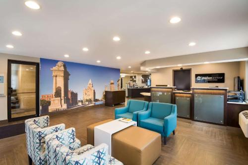 a hotel lobby with blue chairs and a bar at Clarion Pointe Downtown in Syracuse