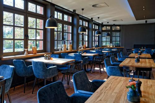 a restaurant with wooden tables and blue chairs at ATLANTIC Hotel Landgut Horn in Bremen