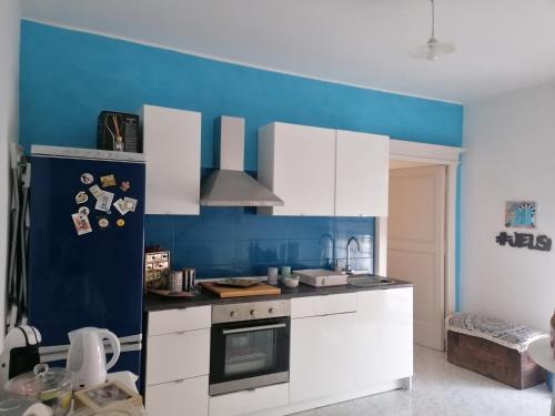 a kitchen with white cabinets and a blue wall at Demetra Piccola Casa Vacanze in Ielsi
