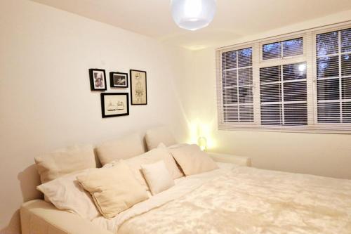 a bedroom with a white bed and a window at Beautiful Peaceful Cottage Overlooking The Museum in Weybridge