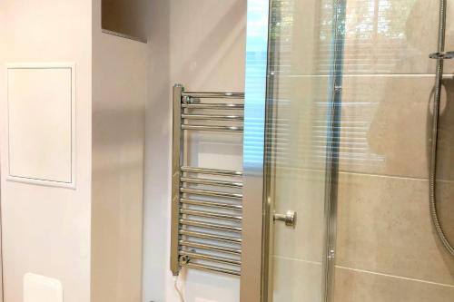 a bathroom with a shower with a glass door at Beautiful Peaceful Cottage Overlooking The Museum in Weybridge