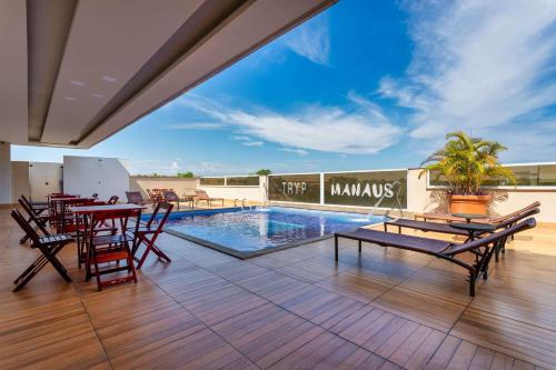 a patio with tables and chairs and a swimming pool at TRYP by Wyndham Manaus Aeroporto in Manaus