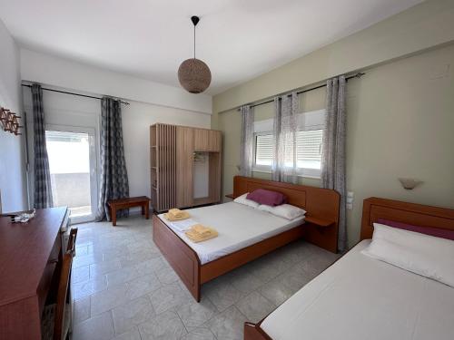 a bedroom with two beds and a desk and windows at Voula Beach in Léntas