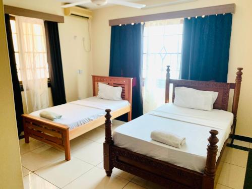 2 letti in una camera con tende blu di Lux Suites Furaha Holiday Apartments Nyali a Mombasa