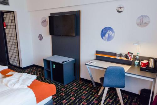 a hotel room with a desk and a bed and a chair at Vienna House Easy by Wyndham Bucharest Airport in Otopeni