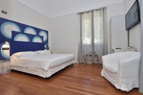 a white bedroom with a bed and a chair at Villa Lara Hotel in Amalfi