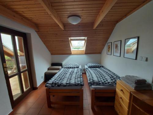 a bedroom with two beds and a wooden ceiling at Sklípek u kapličky in Velké Bílovice