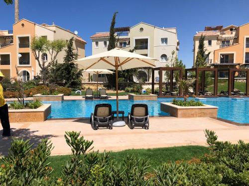 a pool with two chairs and an umbrella at Bait Karim - Twin Villa with roof & juccuzi in Ras Elhekma