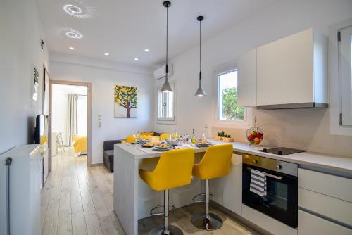 a kitchen with a counter and yellow chairs in it at White Rock Milos Suites in Adamas