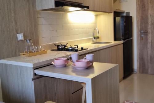 a kitchen with a counter with three bowls on it at Apt Pejaten Park 1BR Latte w/ Netflix in Jakarta