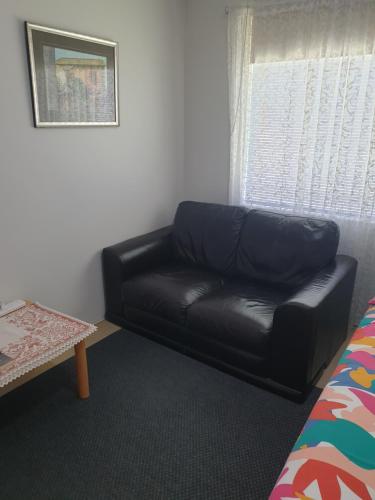 a black leather couch in a room with a window at Telperio - Guest suite max 4 Guests in Bunbury