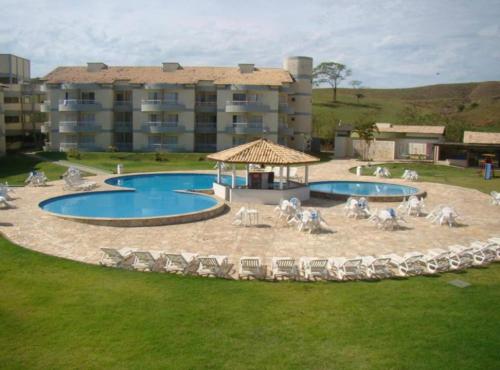 a resort with a pool and chairs and a building at Flat Village - Aldeia das Águas in Barra do Piraí