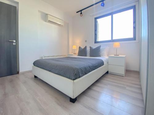 a white bedroom with a bed and a window at Phaedrus Living: City Flat Rafaella 6 in Nicosia