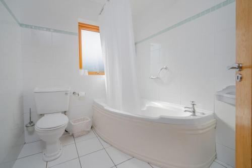 baño blanco con bañera, aseo y lavamanos en The Moorings- near the sea en Tramore
