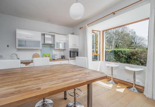 a kitchen with a wooden table and a large window at The Moorings- near the sea in Tramore