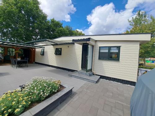 a small white house with a patio and a table at Chalet Zeeweg in Nunspeet