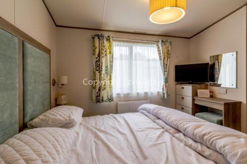 - une chambre avec un lit, une télévision et une fenêtre dans l'établissement Luxury 6 Berth Caravan For Hire At Broadlands Sands Holiday Park Ref 20340bs, à Hopton on Sea