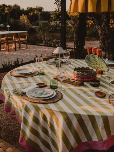 a table with a striped table cloth with plates and wine glasses at Amagatay Luxury Boutique Hotel - Adults Only in Alaior