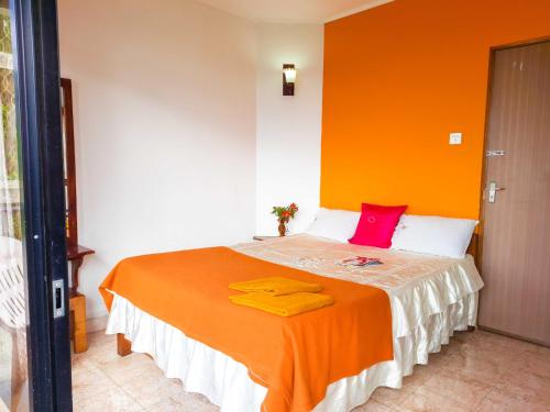a bedroom with a bed with an orange wall at Awinco Haputale in Haputale