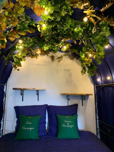Cette chambre dispose d'un lit avec des oreillers et des lumières verts. dans l'établissement L’INSOLITE, à Pierry