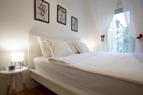 a white bedroom with a bed and a window at Vedrana-Free garage in Zagreb
