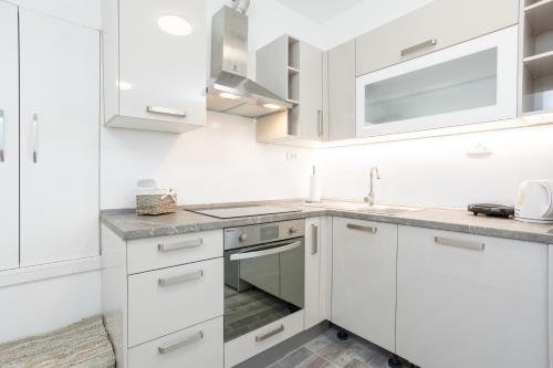 uma cozinha branca com armários brancos e um lavatório em Residence Marina em Split