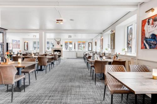 Hotel Hjallerup Kro في Hjallerup: غرفة طعام مع طاولات وكراسي ومدفأة