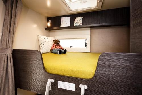 un osito de peluche sentado en una cama en una caravana en Camper met sauna en zwembad in de rand van de Vlaamse Ardennen en Haaltert