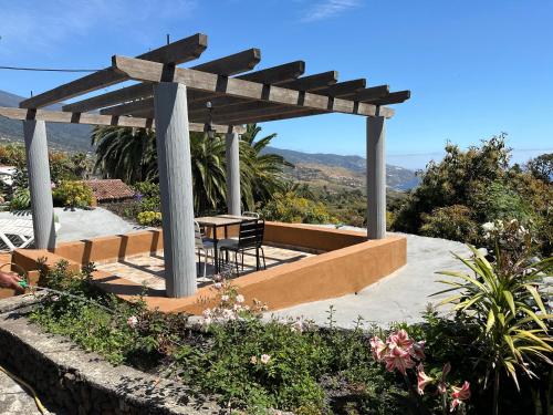 a wooden pergola with a table and chairs in a garden at Casa Asuncion in Breña Alta