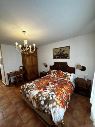 a bedroom with a bed and a chandelier at La Ventana De Tejera Negra in Cantalojas