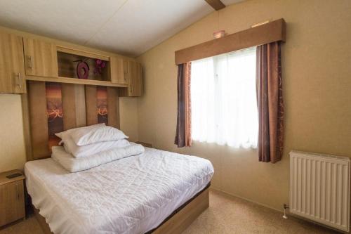a bedroom with a large bed with a window at Beautiful 8 Berth Caravan At Cherry Tree Holiday Park In Norfolk Ref 70803c in Great Yarmouth