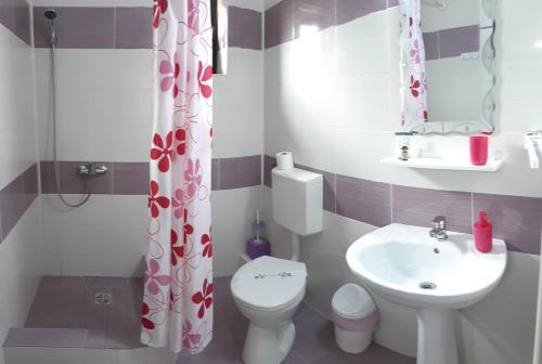a bathroom with a white toilet and a sink at Vila Bya in 2 Mai